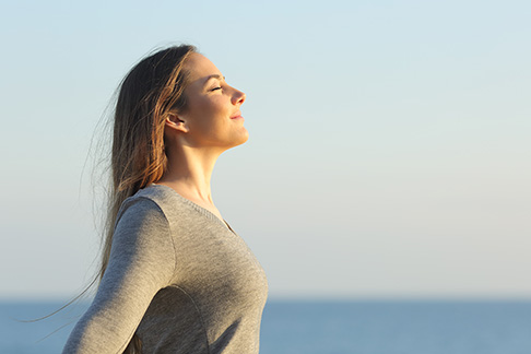 Retrato de vista lateral de uma mulher relaxada respirando ar fresco na praia